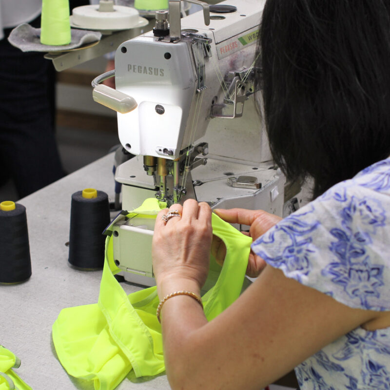An image of a worker in a factory sewing some fabric
