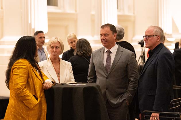 Hon. Colin Brooks Minister for Industry and Advanced Manufacturing Minister for Creative Industries and Ms Bronwyn Halfpenny standing at a high table at the launch Ethical Clothing Australia Week.
